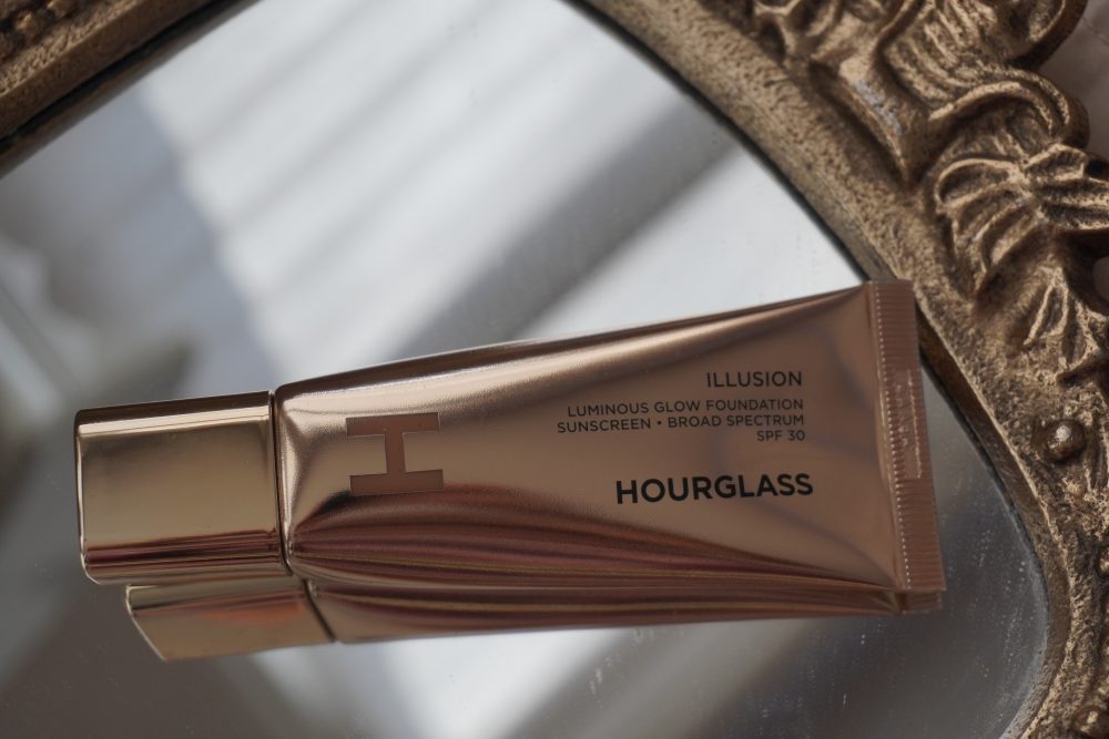 Hourglass Illusion Luminous Glow Foundation SPF 30 gold tube packaging in flat lay, highlighting luxury design and SPF foundation for spring makeup
